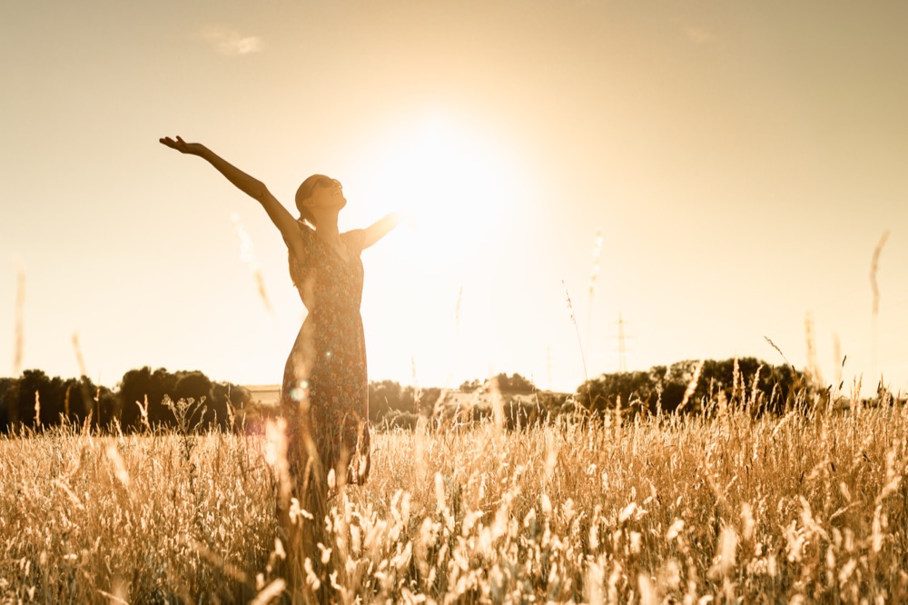 Joyful Person Raising Arms morning in Rural Field Under Summer Sunlight